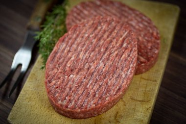 Tahta kesme tahtasının üzerinde iki kıymalı biftek..