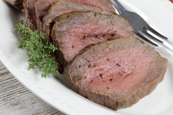 Delicious sliced beef steak with rosemary on a plate