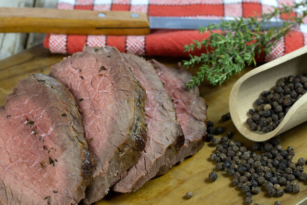Delicious sliced beef steak with rosemary and pepper on wooden board