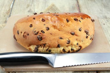 Tahta kesme tahtasının üzerinde çikolata parçacıkları olan Brioche.