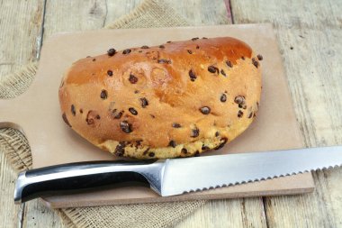 Tahta kesme tahtasının üzerinde çikolata parçacıkları olan Brioche.