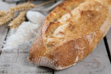 Tahta bir masada un ile taze pişmiş ekmek