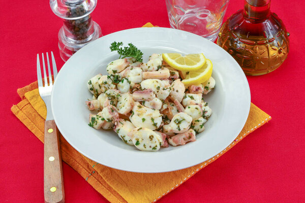 Octopus pieces cooked with garlic and parsley on a plate.