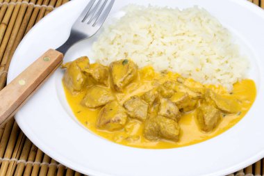 Köri soslu tavuk parçaları ve tabakta pilav..