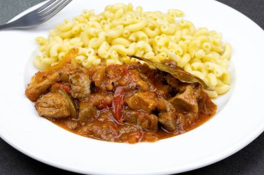 Domates sosu ve makarna ile pişirilmiş domuz parçaları..