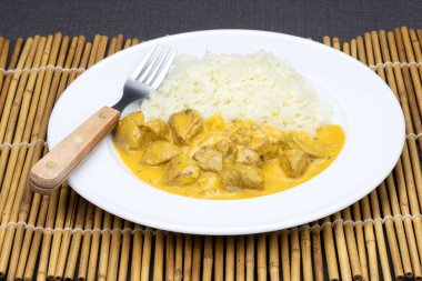 Köri soslu tavuk parçaları ve tabakta pilav..