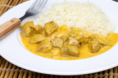 Köri soslu tavuk parçaları ve tabakta pilav..