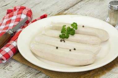 Beyaz kanlı sosisler, beyaz tabakta beyaz puding.