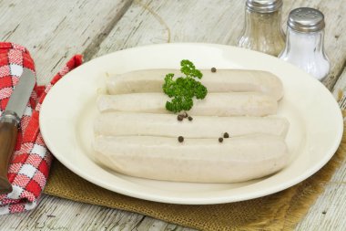 Beyaz kanlı sosisler, beyaz tabakta beyaz puding.