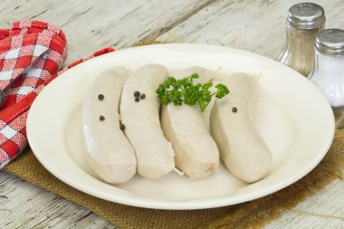 Beyaz kanlı sosisler, beyaz tabakta beyaz puding.