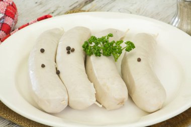 Beyaz kanlı sosisler, beyaz tabakta beyaz puding.