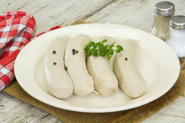 Beyaz kanlı sosisler, beyaz tabakta beyaz puding.