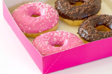 Beyaz arka planda pembe ve çikolata kaplı donutlar.