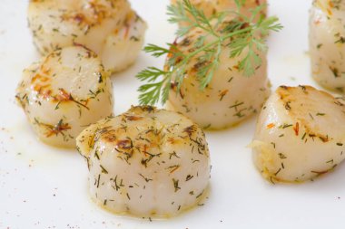 Deniz tarakları beyaz bir tabakta pişiyor. 