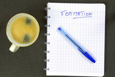 Bir fincan kahve ve metin formasyonlu defter. 