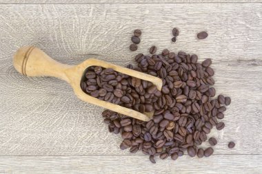 Tahta arka planda tahtadan kepçeyle kahve çekirdekleri.