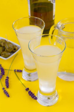 Sarı masada bir bardak pastis. 