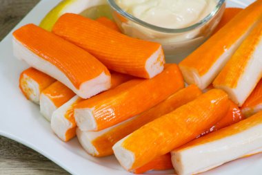 Tabakta sos olan surimi çubukları.