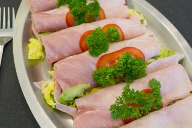 Bir tabağa sarılmış jambon dilimleri