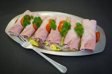 Bir tabağa sarılmış jambon dilimleri