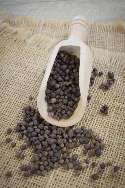 Zwarte Peperkorrels Een Houten Bolletje Rustieke Achtergrond — Stockfoto