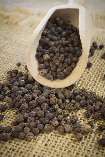 Zwarte Peperkorrels Een Houten Bolletje Rustieke Achtergrond — Stockfoto