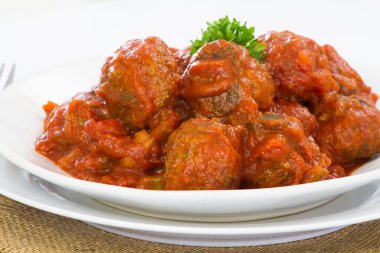 Domates soslu köfteler, beyaz tabakta etli börekler. 