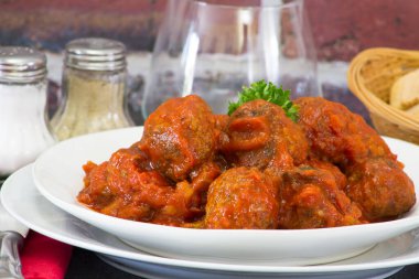 Domates soslu köfteler, beyaz tabakta etli börekler. 