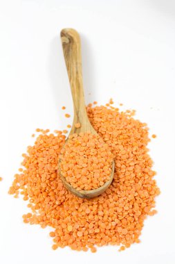 Beyaz arka planda izole edilmiş tahta kaşıkta kırmızı mercimek.