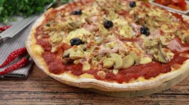 Tahta bir masada jambonlu ve mantarlı pizza.
