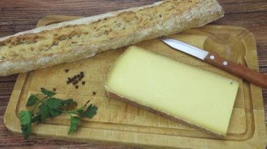 Peynir dilimi, ekmek somunu ve bıçak kesme tahtasında.