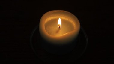 Masadaki karanlık bir odada yanan küçük bir mum.
