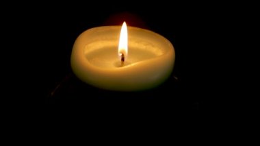 Masadaki karanlık bir odada yanan küçük bir mum.