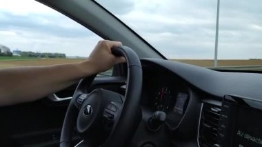 Arabayı süren adam, elleri direksiyonda, yakın plan. 