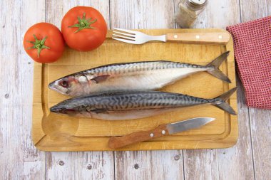 Kesme tahtasındaki bütün ve çiğ uskumru.