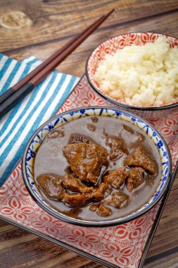 Bir tabakta soğanlı ve pirinçli biftek.