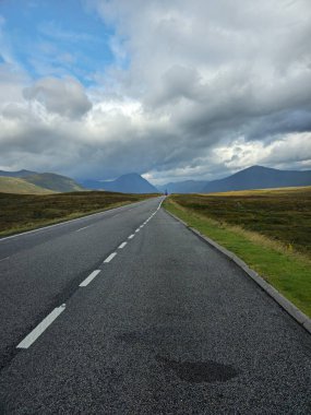 Bir İskoç yolu bulutlu bir gökyüzünün altında İskoçya 'yı geçiyor