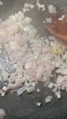 Tavada pişirirken dilimlenmiş arpacık soğanı.