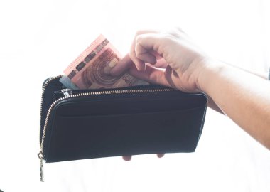 Para çekmek için çantasını açan bir kadın.