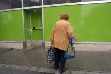 Sokakta bavulları olan yalnız yaşlı bir kadın.