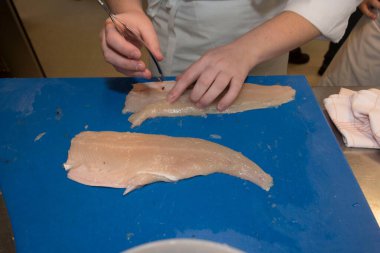 Aşçı mutfakta taze balık filetosu hazırlıyor.