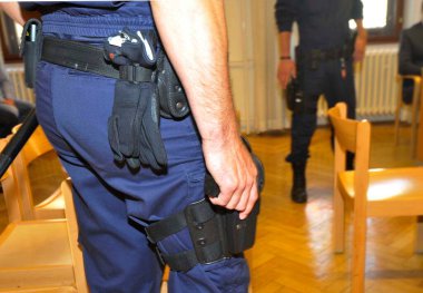 Mahkeme salonunda bir polis memurunun hizmet silahı var.