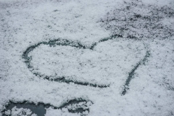 a white heart drawn in the snow on a winter day