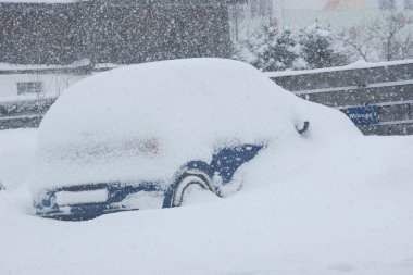 Bir kış günü otoparkta karla kaplı bir araba.