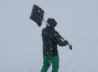 İnsanlar kar yağarken bir kış günü kar kürür.