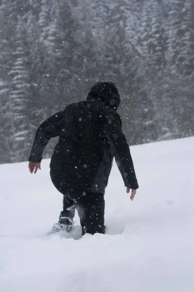 person in black clothing walking in deep snow, snowy winter day