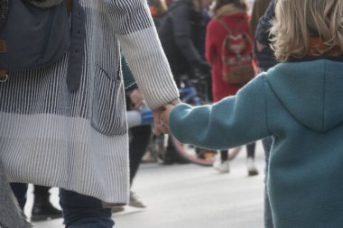 Çocuk ve anne el ele tutuşuyor, güven ve yakınlık işareti.