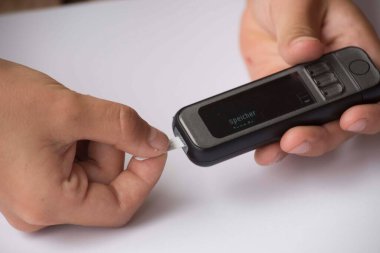 Kan şekeri seviyesini kan şekeri sayacıyla ölçüyor.