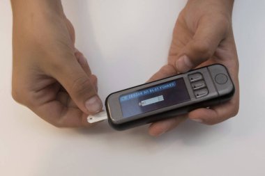 Kan şekeri seviyesini kan şekeri sayacıyla ölçüyor.