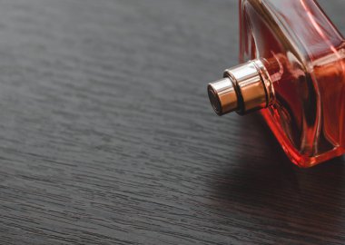 Tahta masadaki kırmızı parfüm şişesi. Yaklaş.